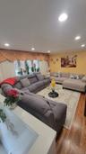 Spacious living area featuring wood-finish flooring, recessed ceiling lights, and a large window with draped valances