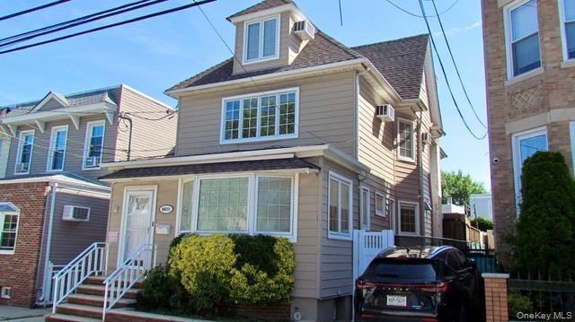 Three-story residence featuring light-toned siding, a dormer window, and a bay window on the first floor