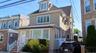 Three-story residence featuring light-toned siding, a dormer window, and a bay window on the first floor