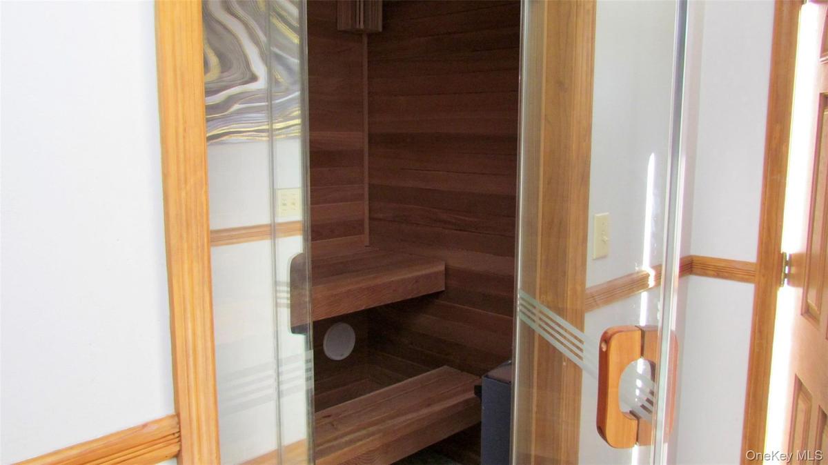 Integrated sauna with clear glass door, wooden handle, and tiered wooden benches