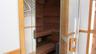 Integrated sauna with clear glass door, wooden handle, and tiered wooden benches
