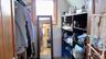 Dedicated walk-in closet space featuring a built-in shelving unit, natural wood trim around a window, and a wood-finish door frame