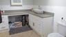 Bathroom vanity with a vessel sink, gray countertop, and white cabinetry
