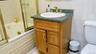 Bathroom vanity with a green countertop, integrated sink, and brass-tone fixtures