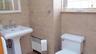 Pedestal sink with chrome faucet set, tiled walls, and leaded glass window
