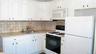 Kitchen featuring white cabinetry, light-toned countertops, a square tile backsplash, and a stainless steel sink