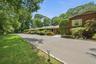 Curving asphalt driveway bordered by stone edging and landscape lighting