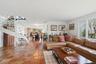 Open-concept living area featuring terracotta tile flooring, a white spiral staircase, and large windows