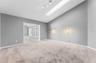large primary bedroom looking towards bonus room with skylight and shade