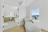 Bright interior space with light wood-finish flooring, white walls, and a window framing a water scene