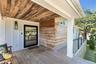 Covered porch featuring a wood-plank ceiling, wood-finish flooring, and white paneled walls