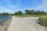 Sandy private beach shoreline with calm waters and natural vegetation along the dunes