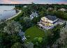 Waterfront residence featuring multiple expansive outdoor decks, a large manicured lawn, a detached gazebo, and a private beach with a dock