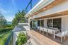 Expansive outdoor deck featuring wood-finish flooring, a built-in outdoor kitchen with grill and sink, and a cable railing system