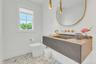 Floating vanity with integrated sink, gold-finish fixtures, and a large oval mirror