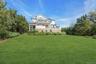 Expansive green lawn bordering a multi-level deck and white shiplap exterior