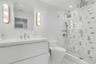 Modern bathroom featuring a glass-enclosed shower with dual shower heads, mosaic tile shower surround, and pebble-finish floor