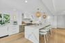 Gourmet kitchen featuring a waterfall island with integrated seating, professional-grade range, full-height cabinetry, wood-finish flooring, and reces