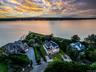 Waterfront property featuring extensive shoreline frontage, multiple residential structures, mature trees, and a private dock structure