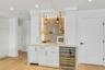 Built-in bar featuring white cabinetry, a stone countertop, a stainless steel beverage refrigerator, icemaker and open floating shelving with integrat