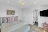 Guest Bedroom with Light wood-finish flooring complements white walls with recessed lighting and a central decorative fixture