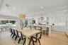Open-concept kitchen and dining area featuring light wood-finish flooring, white cabinetry, a waterfall island, and recessed lighting