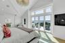 Spacious bedroom featuring vaulted ceilings, a contemporary ceiling light fixture, wood-finish flooring, and a sliding glass door leading to an outdoo