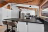 Kitchen featuring a long breakfast bar with a solid surface countertop, white cabinetry, stainless steel appliances, and a wood-paneled vaulted ceilin