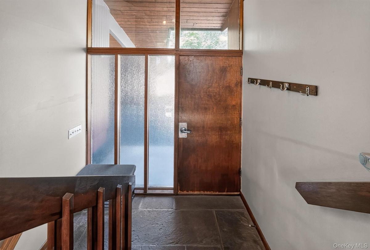 Entryway featuring a rich wood-finish door, slate tile flooring, frosted glass sidelights, clear glass transom, and a wood-finish ceiling
