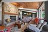 Great room featuring a full-height natural stone fireplace, exposed beam wood-finish ceiling, track lighting, and a ductless mini-split system