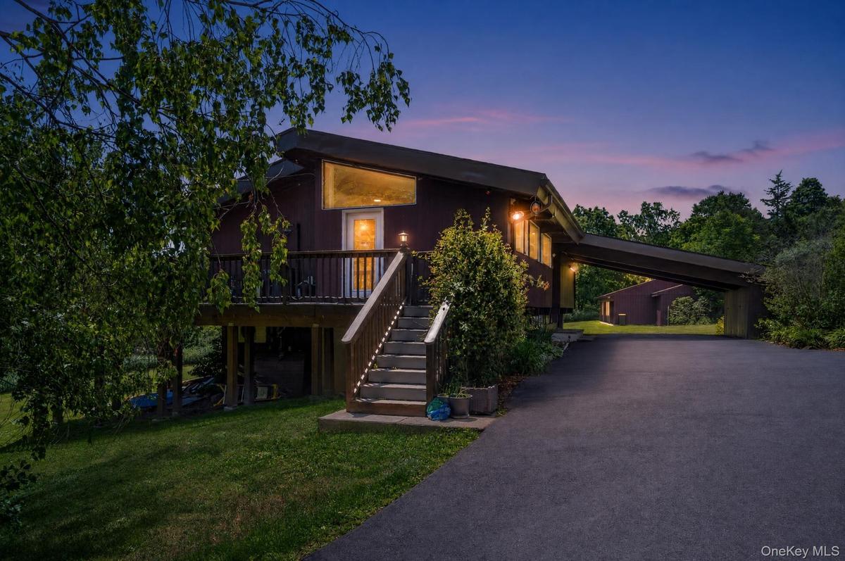 Contemporary-style residence featuring a dark exterior, elevated deck, and prominent exterior staircase