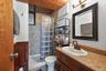 Bathroom featuring a wood-finish ceiling, vanity with a speckled countertop, and a glass block shower enclosure