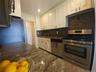 Kitchen featuring granite countertops, a tile backsplash, white cabinetry, and stainless steel appliances