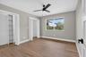 Bedroom featuring wood-finish flooring, a contemporary ceiling fan with integrated lighting, and a large window providing natural light