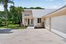 Contemporary stucco exterior with a metal roof, two-car garage, and a modern entry door featuring frosted glass panels