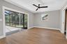 Spacious room featuring wood-finish flooring, a contemporary ceiling fan, and sliding glass doors opening to a screened patio