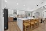 Modern kitchen featuring a waterfall island with a light-toned countertop, two-tone cabinetry, stainless steel appliances, wood-finish flooring, and v