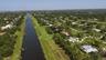 Aerial perspective showcasing a canal-front property amidst a verdant landscape