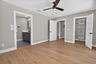 Spacious room featuring wood-finish flooring, light gray walls, and a contemporary ceiling fan