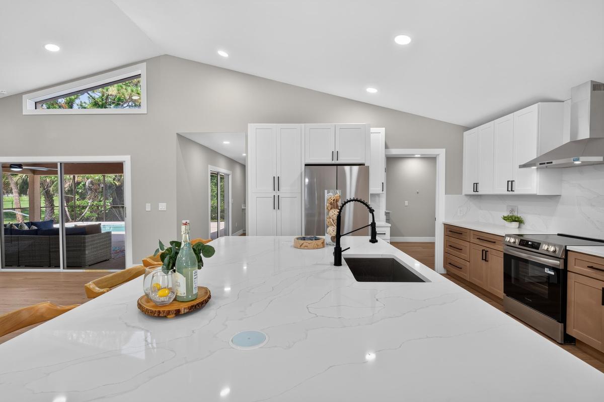 Gourmet kitchen featuring a large island with an undermount sink, a black matte pull-down faucet, and built-in power outlets