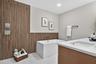Contemporary bathroom featuring a freestanding soaking tub with wall-mounted plumbing fixtures, a wood-finish accent wall, a dual-sink vanity with an 