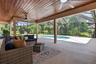 Screened lanai featuring a wood-finish tongue and groove ceiling, dual ceiling fans, ample paved deck space, and a built-in swimming pool