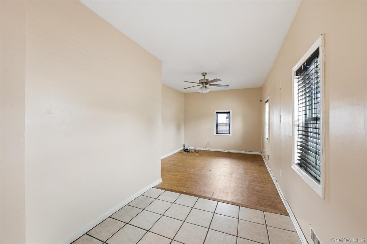 Cozy Living room with a freshly painted neutral color palette, featuring a ceiling fan, multiple windows with blinds