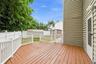 Spacious wooden deck off of the kitchen with white railings to match the white picket fence, a white privacy fence, and a storage shed and pergola for