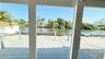 View through sliding door of deck and canal.  Black tarp at seawall is for adjacent unit new pool install.