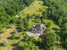 A stunning aerial perspective reveals the harmony of this country estate’s expansive grounds, lush landscaping, open spaces, and wooded backdrop.