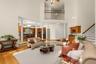 Soaring ceilings, abundant natural light, and a striking floor-to-ceiling brick fireplace create a dramatic yet inviting space for gathering and relax