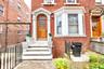 Brick facade with a bay window and arched wooden entry door featuring decorative glass