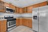 Kitchen featuring stainless steel appliances, light wood cabinetry, and a patterned tile backsplash