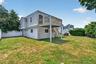 Spacious backyard featuring a multi-level structure with a second-story deck, exterior staircase, and vinyl siding